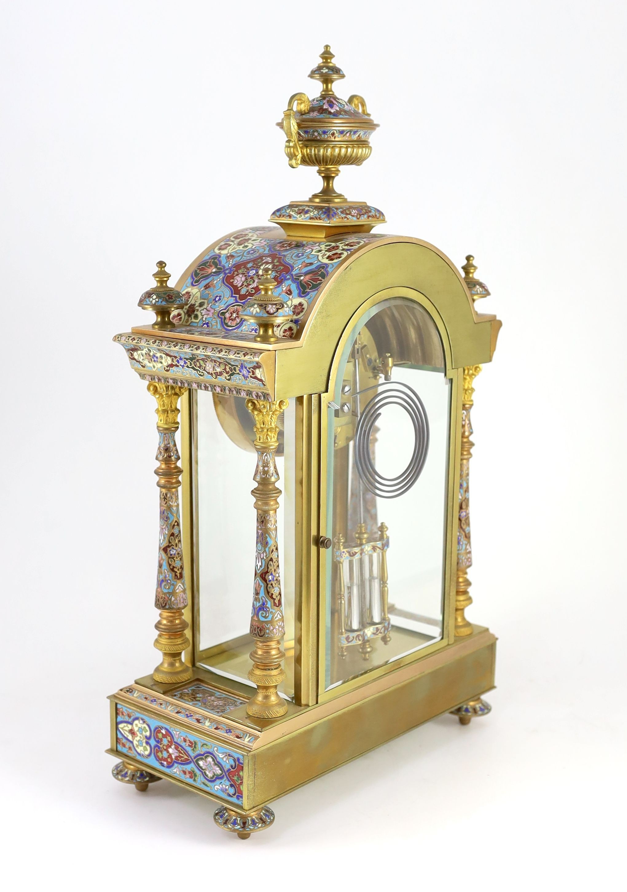 An early 20th century French ormolu and champleve enamel clock garniture, clock: height 50.5cm urns: height 32.5cm